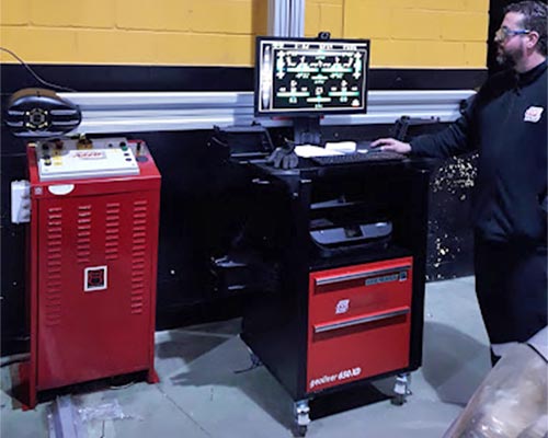 Máquina alineado neumáticos BestDrive Azuaga Mecánico trabajando en máquina de alineado paralelo y equilibrado de neumáticos.